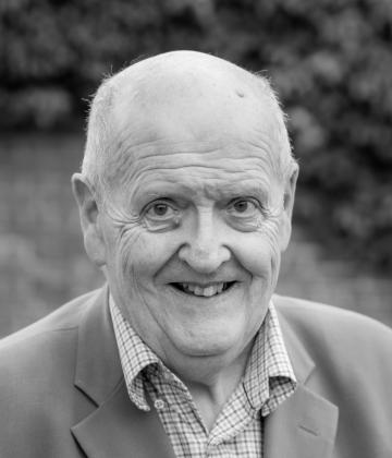 Black and white image of Board member, Martin Price smiling toward the camera 