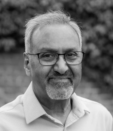 black and white image of board member, Reshard Auladin, smiling towards the camera
