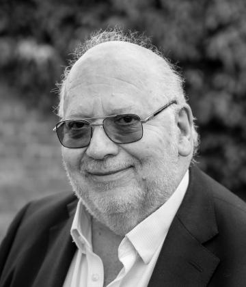 Black and white image of our Board Chair, Toby Harris smiling towards the camera 