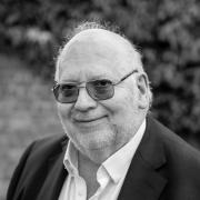 Black and white image of our Board Chair, Toby Harris smiling towards the camera 